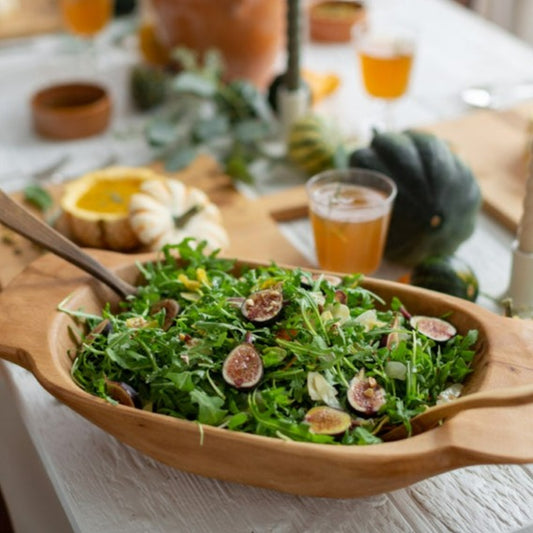Food safe wooden dough bowl by Farmhouse Pottery with a rustic finish, holding a salad.
