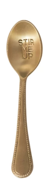 Gold-toned engraved spoon with "Stir Me Up" text, and a textured handle.