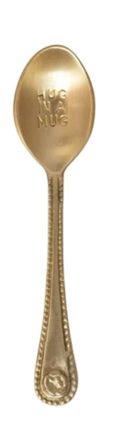 Gold engraved spoon with "Hug in a Mug" text on the head, decorative patterns on the handle.