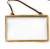 Brass picture frame, horizontal, by Creative Co-Op, with a brown leather strap and brass-colored metal trim.
