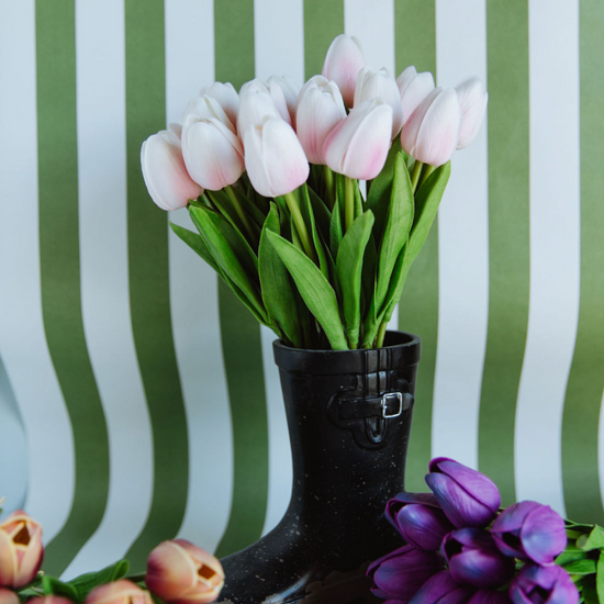 Black rain boot with pink tulips against a green and white striped background