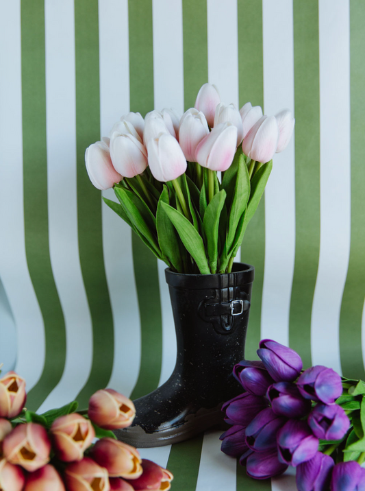 Black rain boot with pink tulips against a green and white striped background