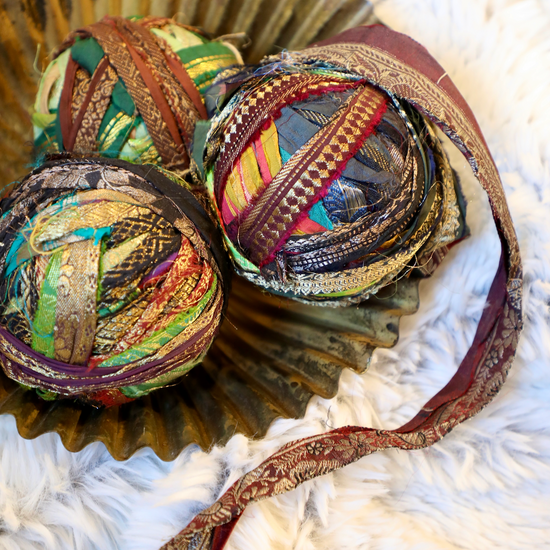 Recycled torn silk sari ribbon with metallic threads from an unknown brand in a decorative gold dish.
