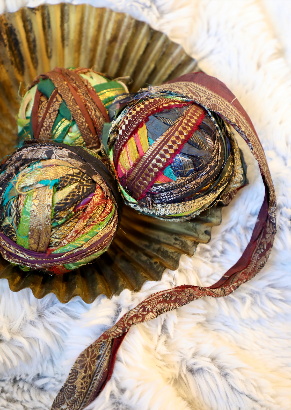 Recycled torn silk sari ribbon with metallic threads from an unknown brand in a decorative gold dish.
