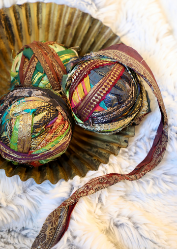 Recycled torn silk sari ribbon with metallic threads from an unknown brand in a decorative gold dish.
