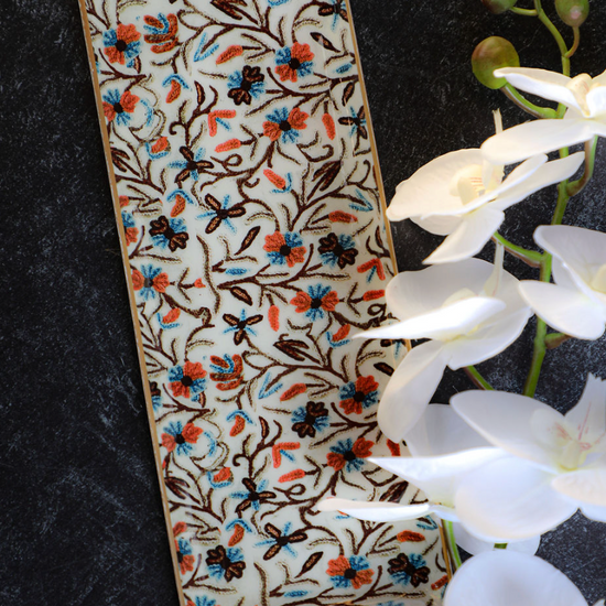Enameled metal tray with gold rim from unknown vendor, featuring a floral pattern with white orchids.
