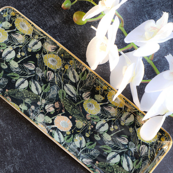 Enameled metal tray with gold rim featuring a floral pattern with white orchids.