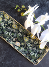 Enameled metal tray with gold rim featuring a floral pattern with white orchids.