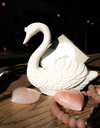 Antique white swan container of cast iron, holding a card, with decorative stones and beads.
