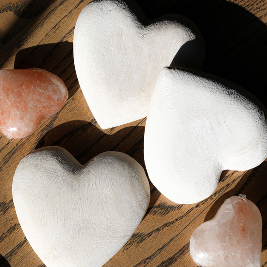 Carved wooden heart by an unknown brand, arranged with pink salt hearts on a wooden table.