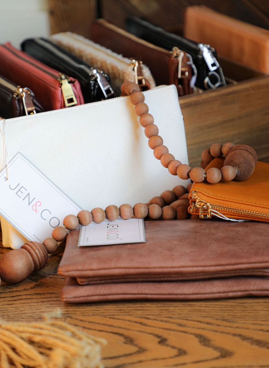 Vegan leather wristlet by Jen&Co, with a wooden beaded strap and multiple zipper pouches.
