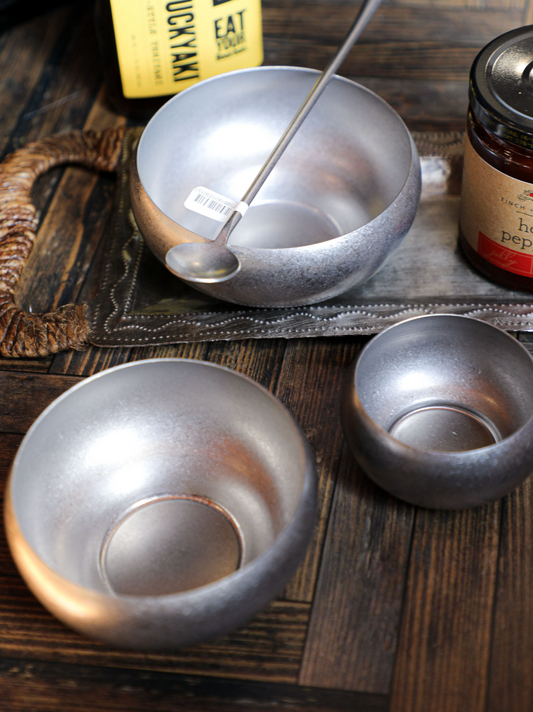 Set of three stainless steel nesting bowls by unknown vendor, with a spoon on a decorative tray.