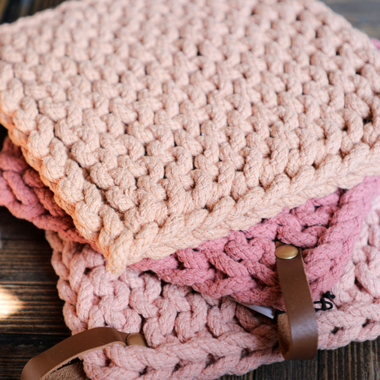 Stacked cotton crocheted pot holders with leather loops by unknown brand, in various shades of pink.