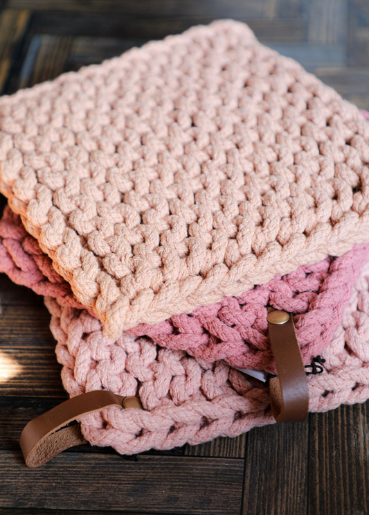 Stacked cotton crocheted pot holders with leather loops by unknown brand, in various shades of pink.