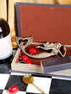 Cast iron mermaid shaped bottle opener by MHW, with a heart-shaped tail and placed among decorative cherries.