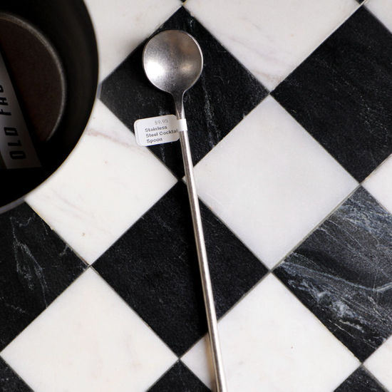 Stainless steel cocktail spoon from Unknown Vendor, lying on a black and white checkered surface.