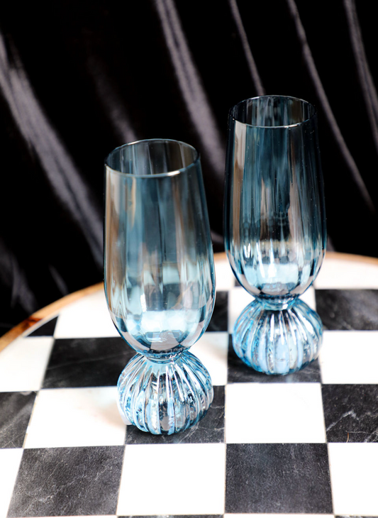 Blue pleated footed champagne glasses by unspecified brand, on a chessboard.