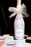 Wrapped prosecco bottle by Beau Bottles with a blue and white floral pattern and a white tulle bow.