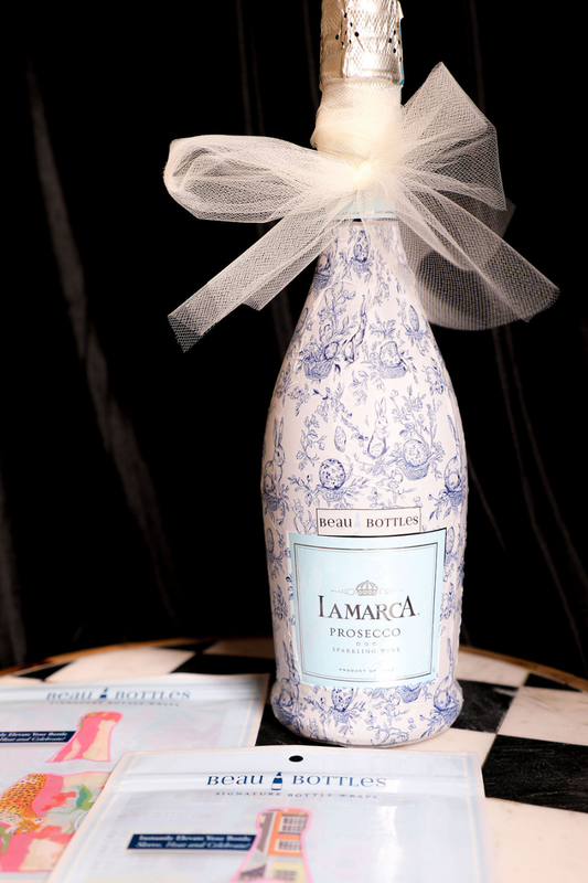 Wrapped prosecco bottle by Beau Bottles with a blue and white floral pattern and a white tulle bow.