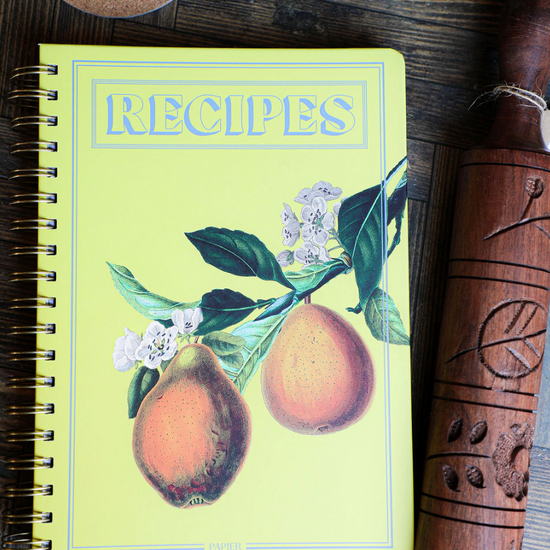 Hanging Fruits hardcover recipe journal by Papier, featuring a spiral binding and pear illustration on yellow.
