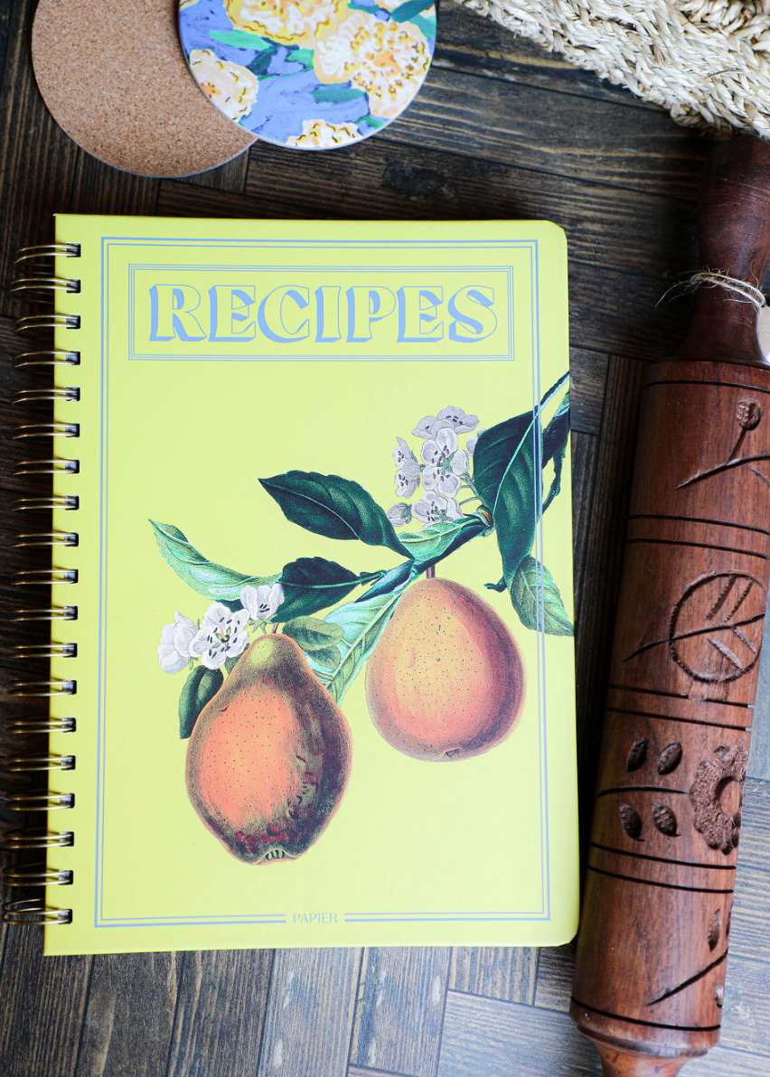 Hanging Fruits hardcover recipe journal by Papier, featuring a spiral binding and pear illustration on yellow.
