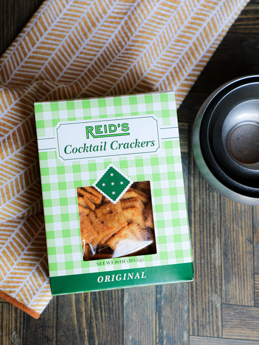 Box of cocktail crackers by Reid's, displayed near a dish towel with a geometric pattern.
