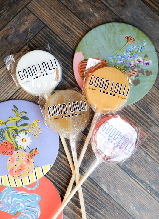 Gourmet lollipops by Good Lolli in clear plastic packaging on a wooden background.