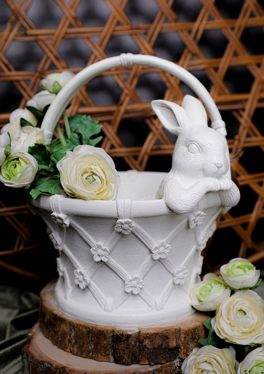 Decorative white rabbit with a basket of flowers on a wooden base against a woven background