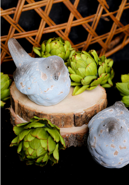 Blue terracotta birds by Foreside Home and Garden, arranged with faux artichokes and wood slices.
