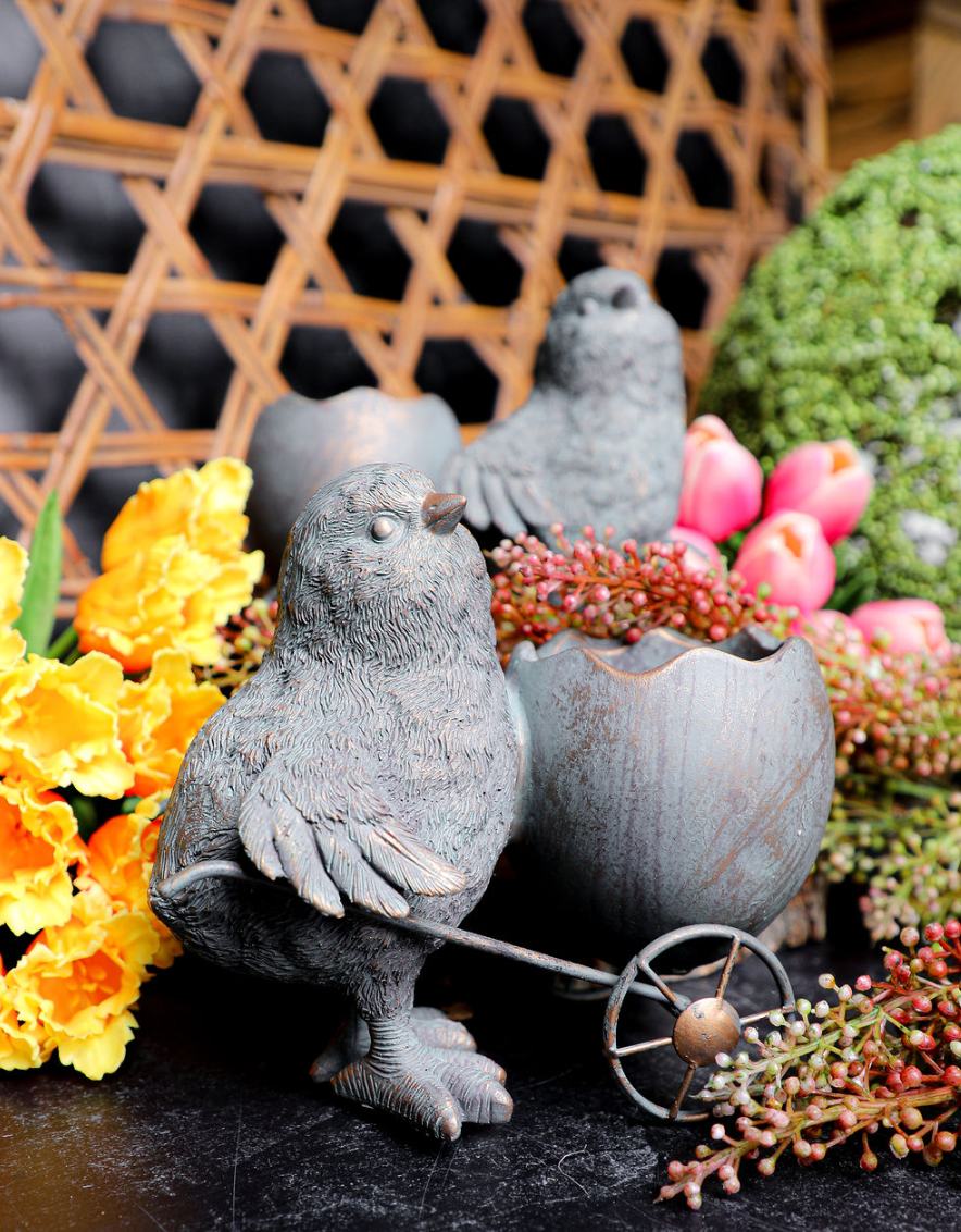 Resin chick with egg cart by Transpac, surrounded by flowers and decorative elements.