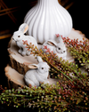 Small gray bunnies on a wood slice, surrounded by faux red berry sprigs.