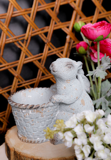 Decorative angel figurine with a crystal bowl on a wooden stand, surrounded by flowers.