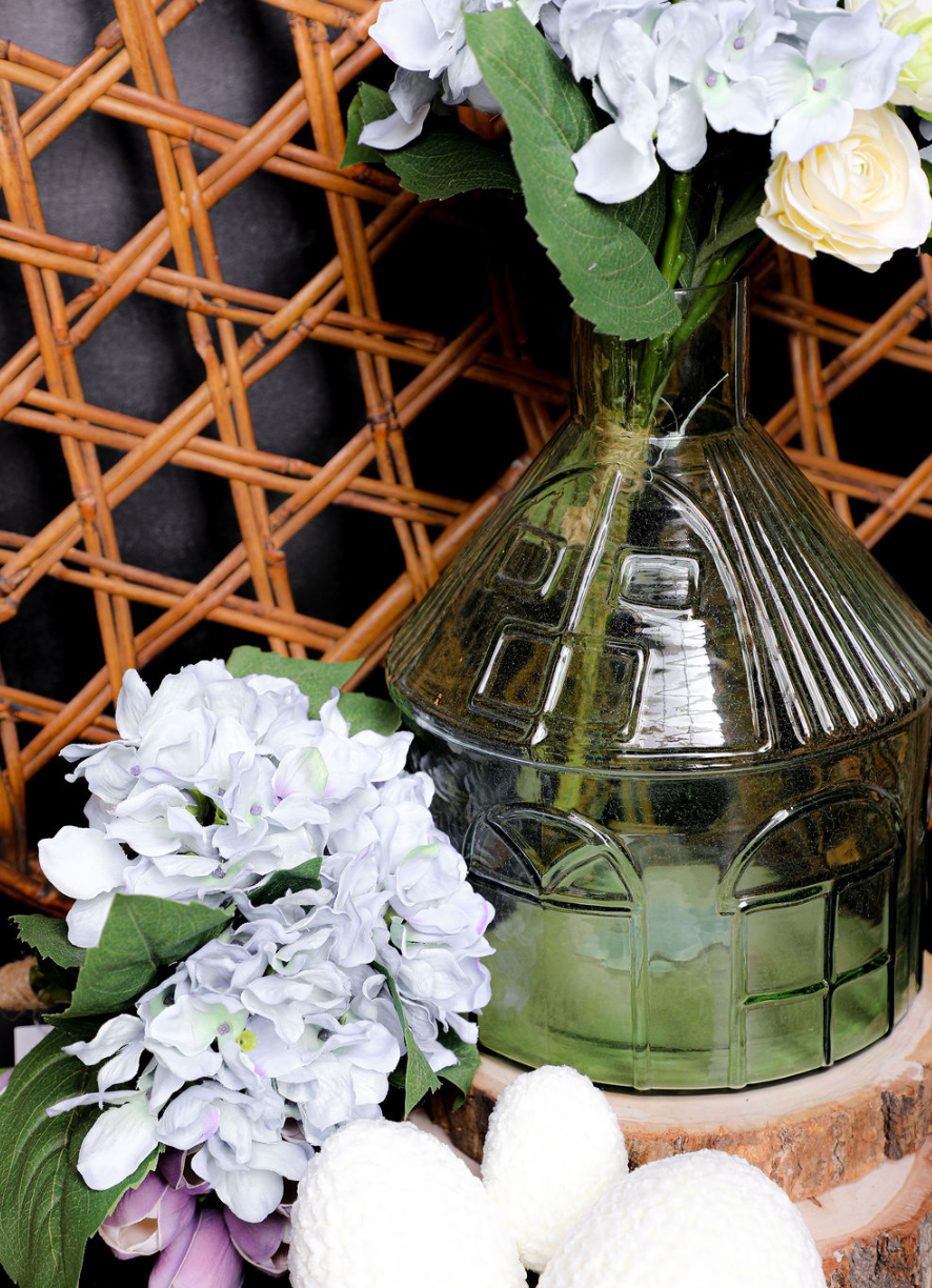 Decorative glass vase with floral arrangement against a woven basket background
