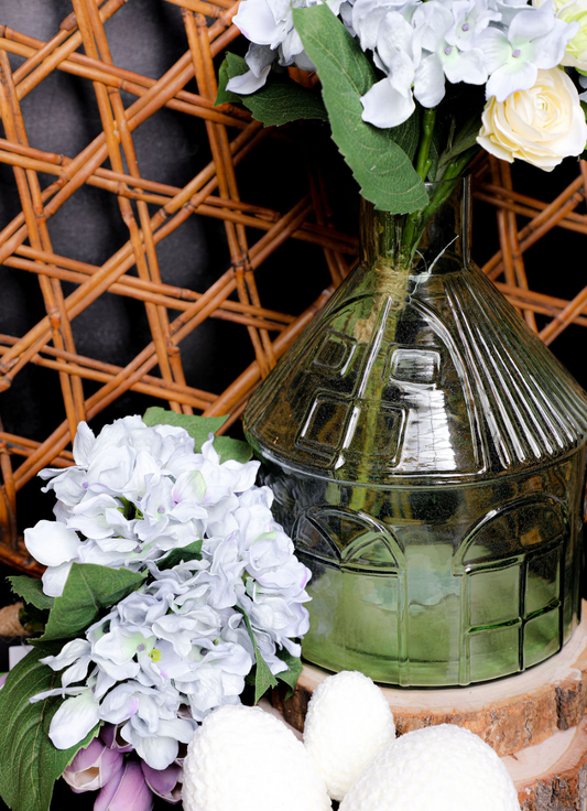 Decorative glass vase with floral arrangement against a woven basket background