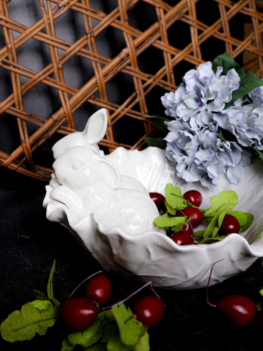 Decorative white bowl with floral and fruit arrangement on a dark background