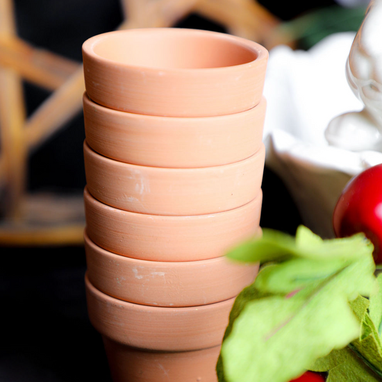 Stack of terracotta pots on a dark surface with a blurred background