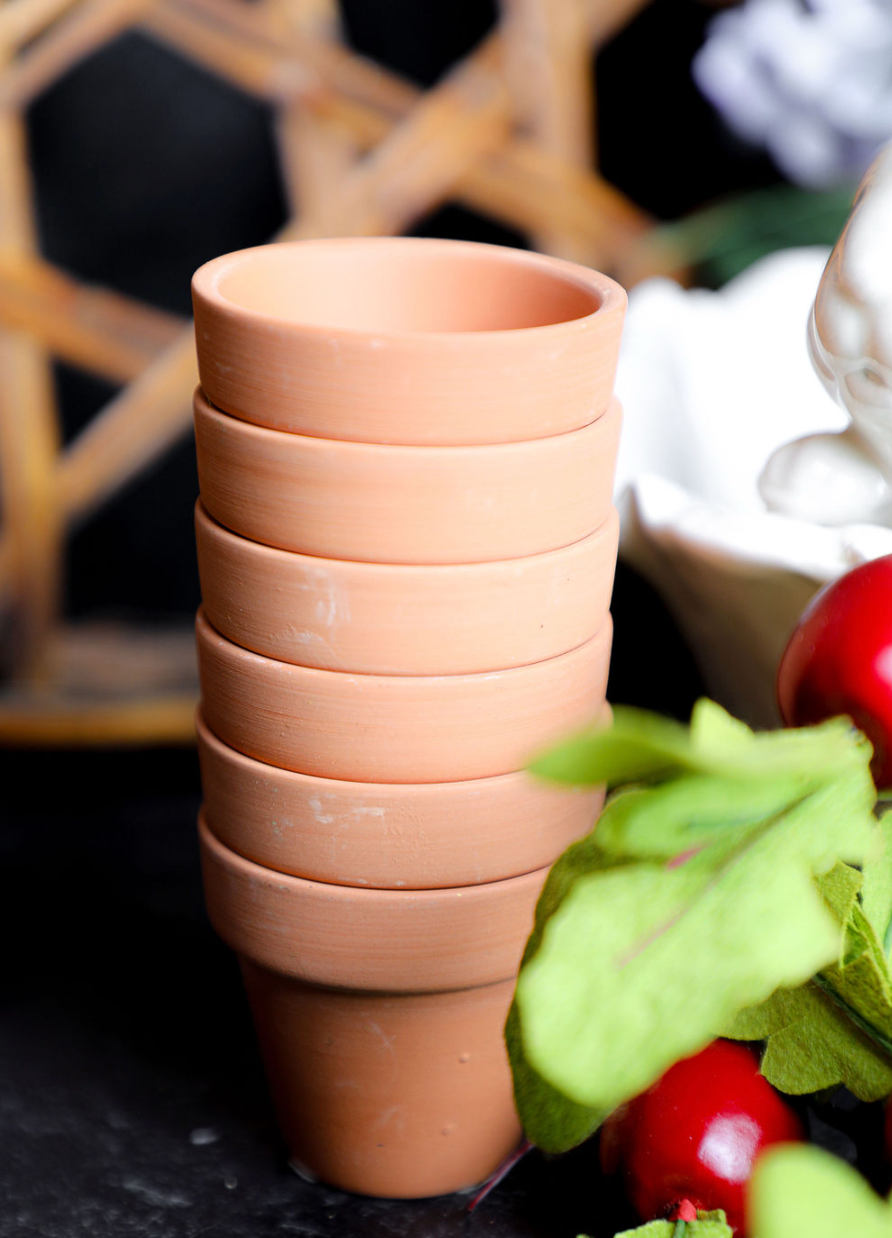 Stack of terracotta pots on a dark surface with a blurred background