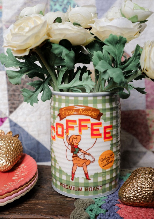 Vintage-style coffee can with a checkered design holding white flowers on a decorative surface.