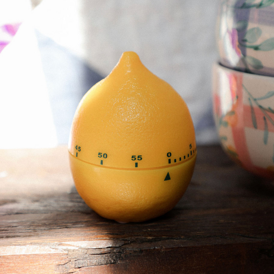Yellow lemon-shaped timer on a wooden surface with a blurred background