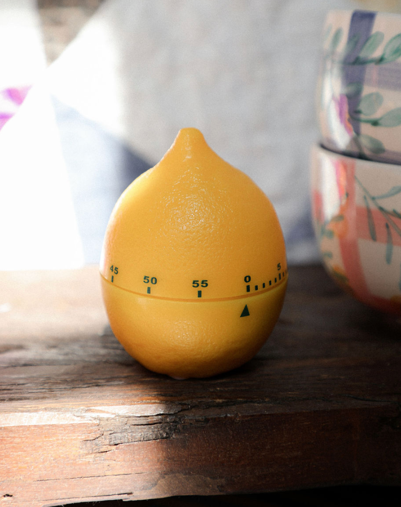 Yellow lemon-shaped timer on a wooden surface with a blurred background