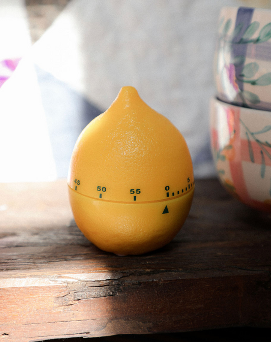 Yellow lemon-shaped timer on a wooden surface with a blurred background