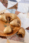 Gold strawberry-shaped objects on a decorative plate with a patchwork quilt background