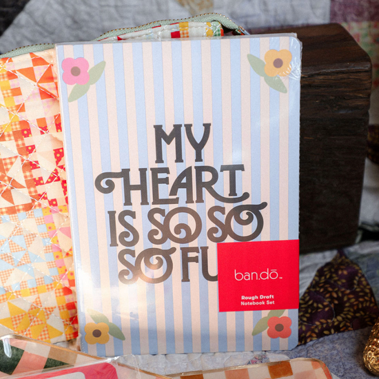 Bando notebook set with colorful designs and text on a textured surface