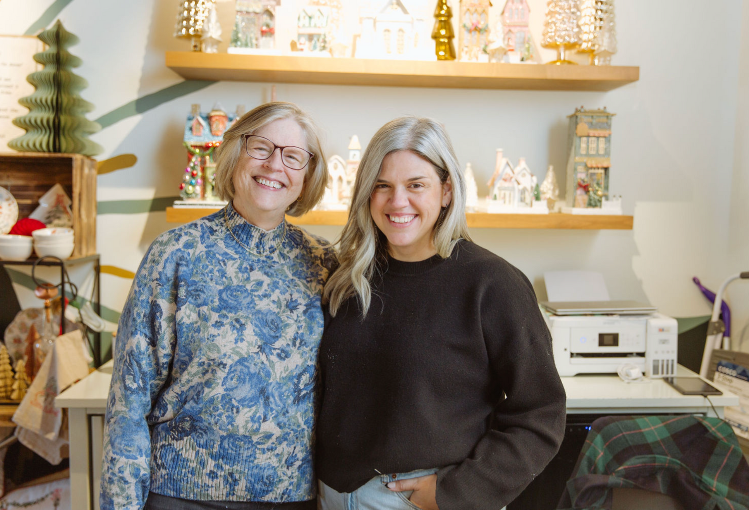 Two women standing together in a store with shelves and products in the background