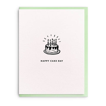 Birthday greeting card with a cake drawing by Smitten on Paper, featuring a simple black-and-white design on textured paper with a pastel green border.
