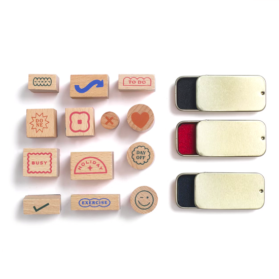 Planner stamp set with wooden blocks from Good Day, shown with ink pads in gold tin cases.