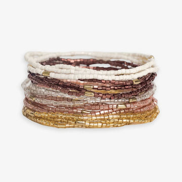 Stack of Chelsea 18 Strand Bracelet Set with neutral, brown, and gold hues.