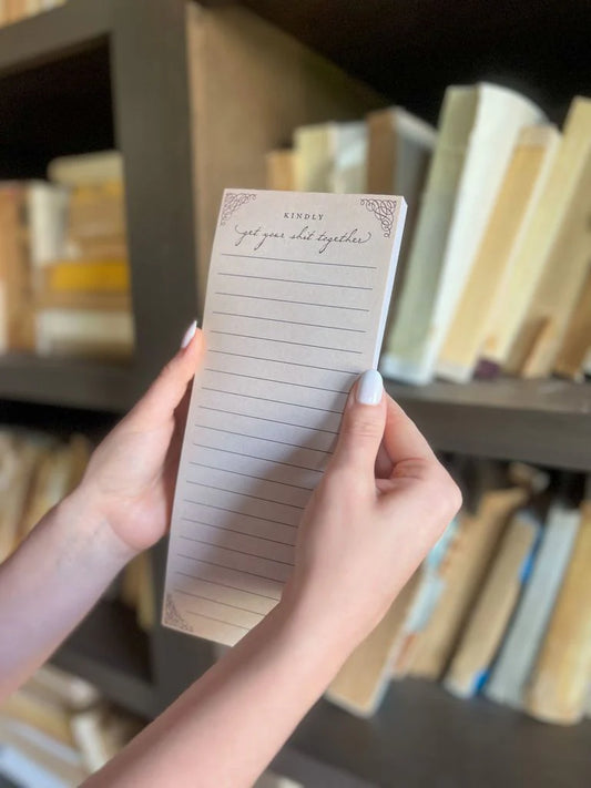 Skinny notepad by Kindly with lined sheets, decorative corner designs, and humorous text.