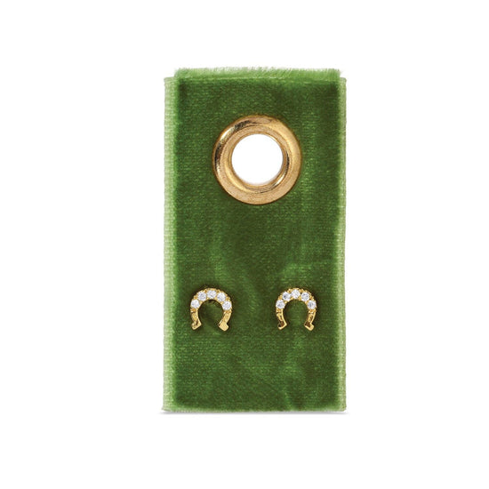 Gold horseshoe stud earrings on a green velvet gift tag.