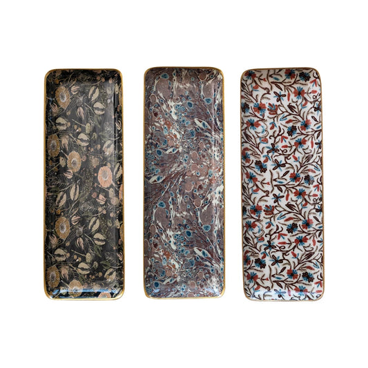 Set of enameled metal trays with gold trim, featuring different patterns.